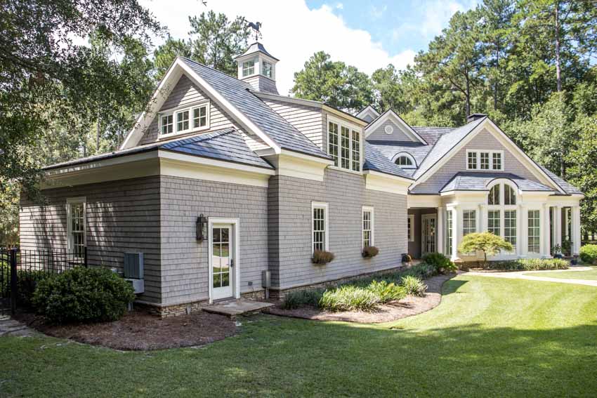 Cape cod house with siding, front porch, windows, pitched roof, and hedged plants