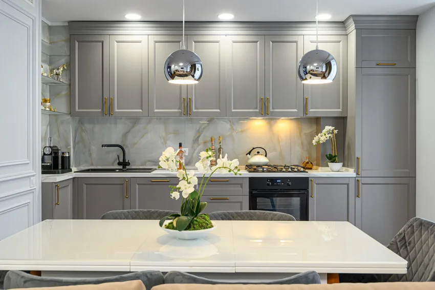 Contemporary kitchen with Calcatta gold backsplash, island, gray cabinets, pendant lights, sink, and faucet