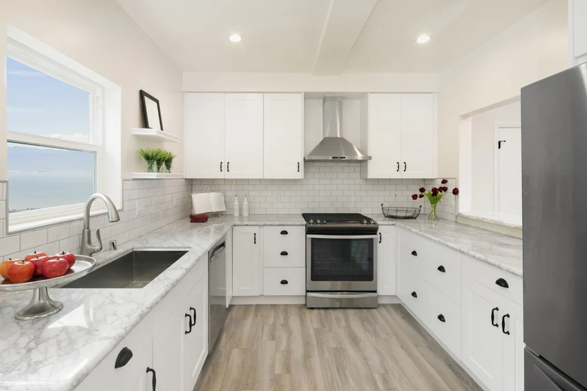 Kitchen with white shaker cabinets, Carrara marble countertop, subway tile backsplash and oven