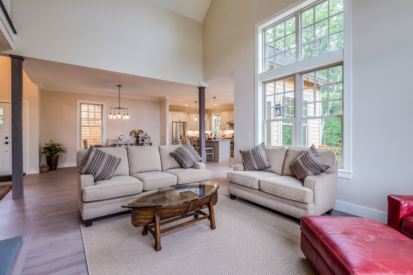 Contemporary living room with a high ceiling, loveseat, couch, coffee table, carpet, wood flooring, and window