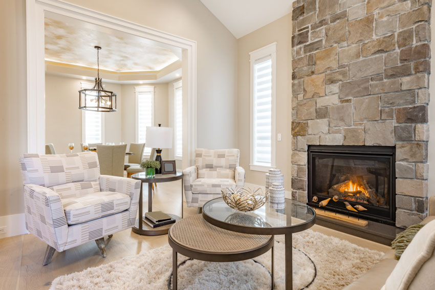 Room with cushioned chairs, glass top table, natural stone wall and sloped ceiling