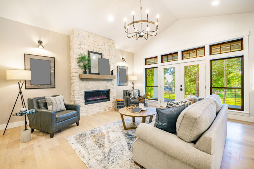 Room with candle style chandelier, upholstered sofa, wall mirror accent and transom windows