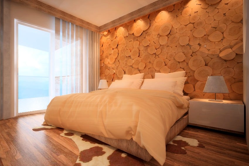 Cozy bedroom with comfortable bed with okoume logs wall accent and glass doors 