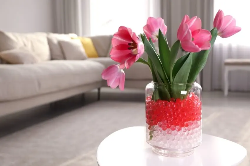 Different color fillers with tulips in vase on white table