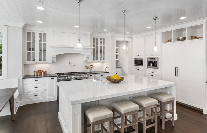 Farmhouse kitchen with beadboard ceiling, island, countertops, stools, pendant lights, cabinets, and wood flooring