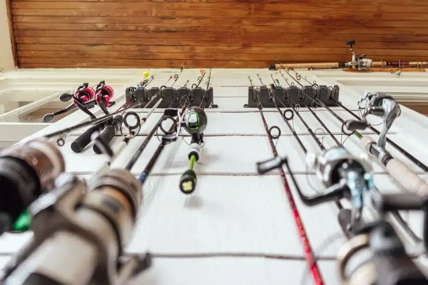 Fishing rods in a holder mounted on a white shingle wall with natural wood ceiling