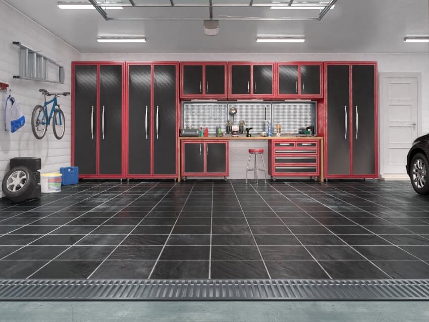 Garage with rolling gate, black tile floor mat, and red and black cabinets