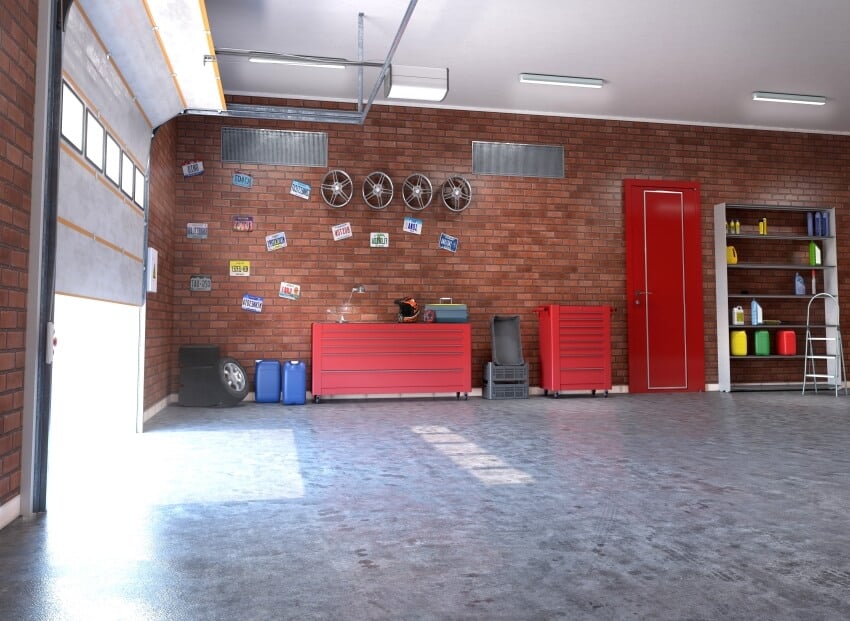 Garage with rolling gate, brick walls, shelves, red storage cabinets, and toolbox