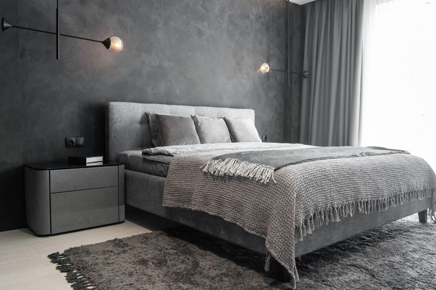 Gray bedroom with grey walls, nightstand with black top and bed with headboard