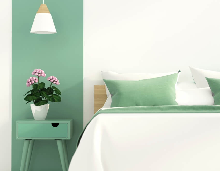Green interior of a modern bedroom with pendant lamp and flower on bedside table