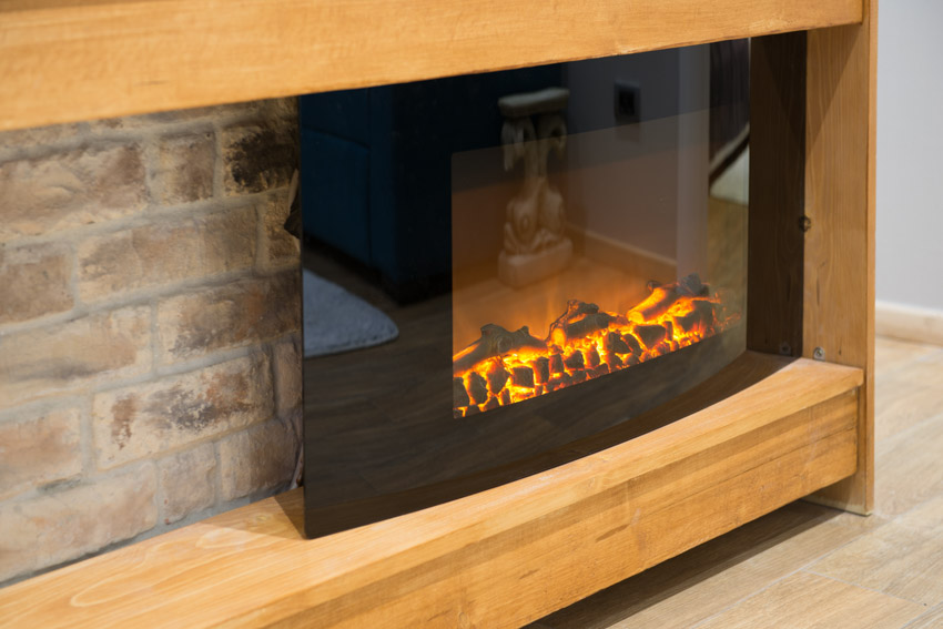 Home with fireplace insert on wood shelf and brick wall 