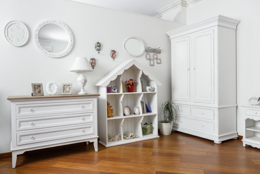 Home interior with white dresser, mirror, wood flooring, decor pieces, and armoire