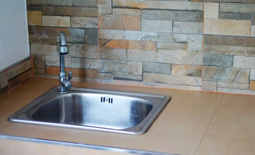Kitchen sink with tile countertop and peel and stick slate backsplash