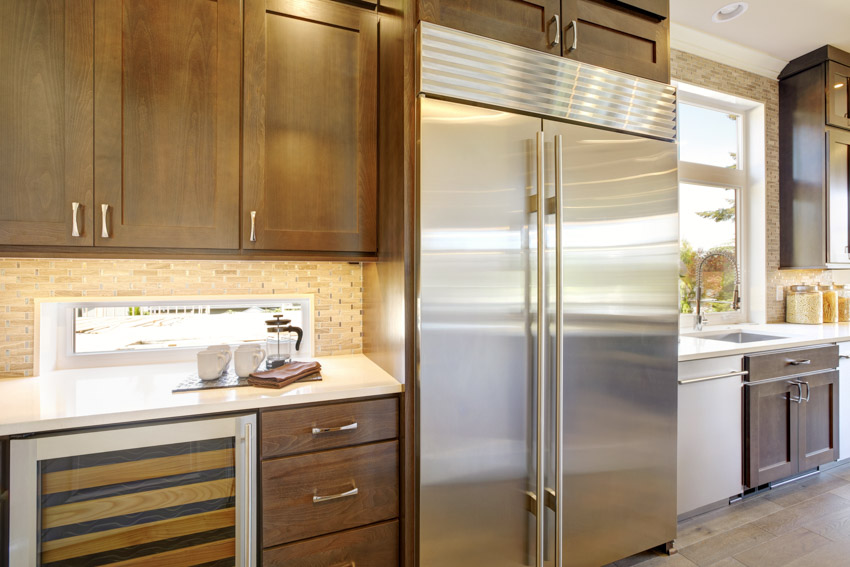 Kitchen with backsplash, cabinets, tile flooring, and refrigerator