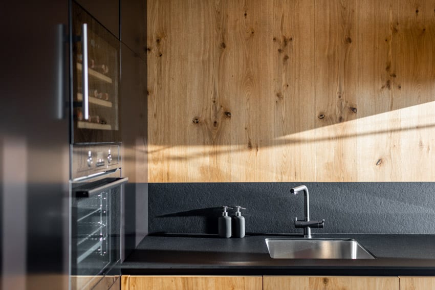 Kitchen with brilliant black quartzite, countertop, wood cabinets, sink, and faucet
