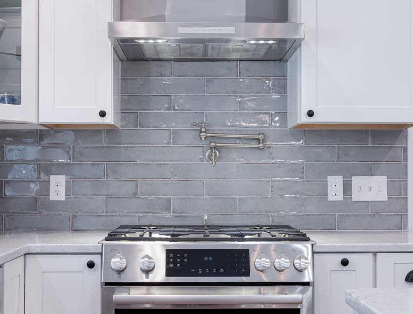 Kitchen with cabinets, stove, and subway glass tile backsplash