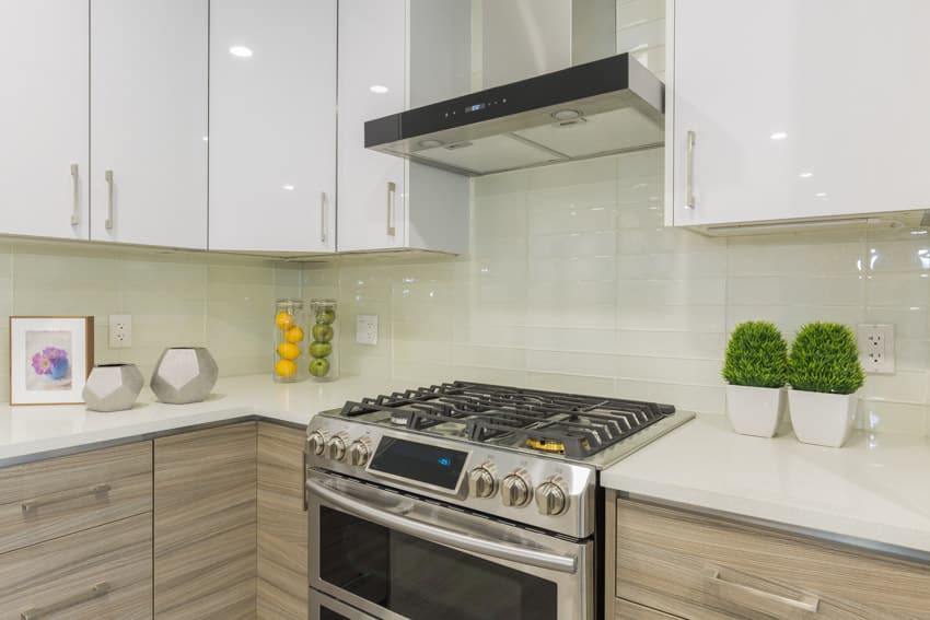 Kitchen with cabinets, stove, range hood, countertops, and glass tile backsplash