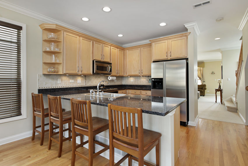 Kitchen with chairs, oak cabinets, countertops, refrigerator, ceilings, and wood flooring