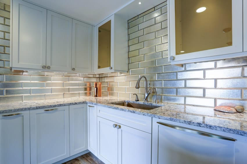 Kitchen with countertop, cabinets, sink, faucet, and glass tile backsplash