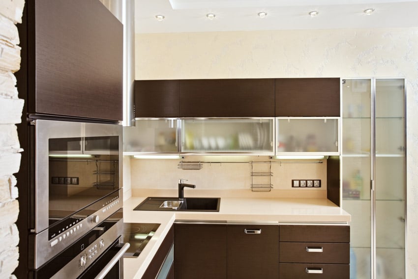 Kitchen with countertops, backsplash, oven, sink and black faucet