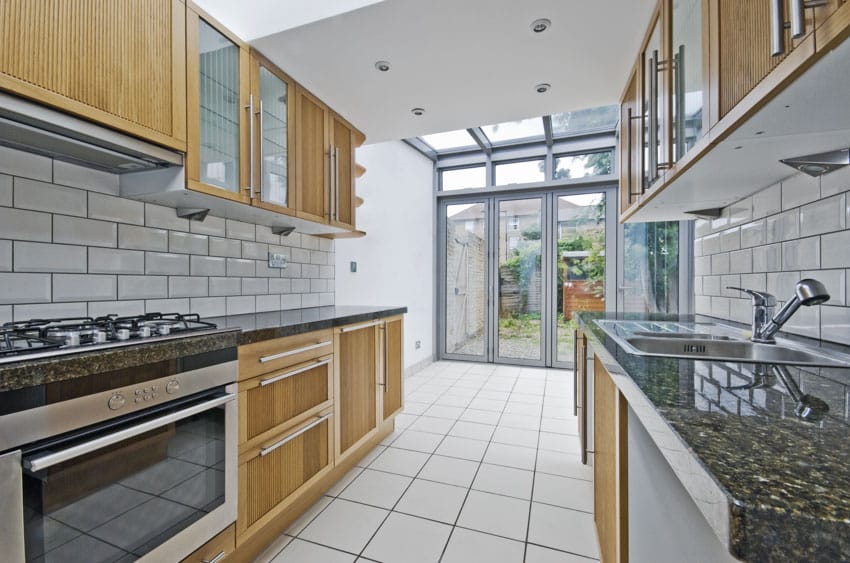 Kitchen with decorative glass insert cabinets, tile backsplash, countertops and tile floors