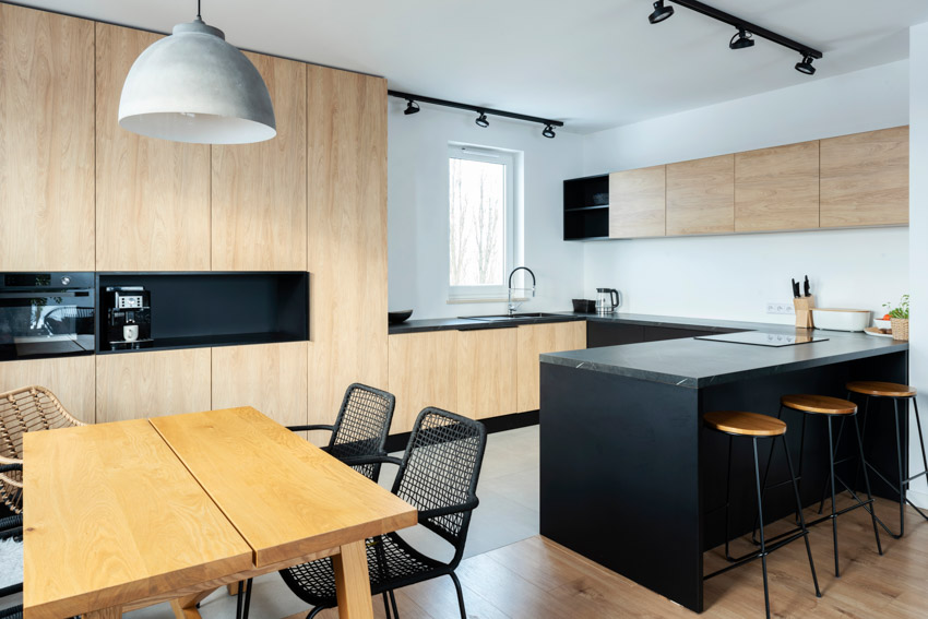 Kitchen with dining table, chairs, bar stools, pendant lights, wood veneer cabinets, window, and backsplash