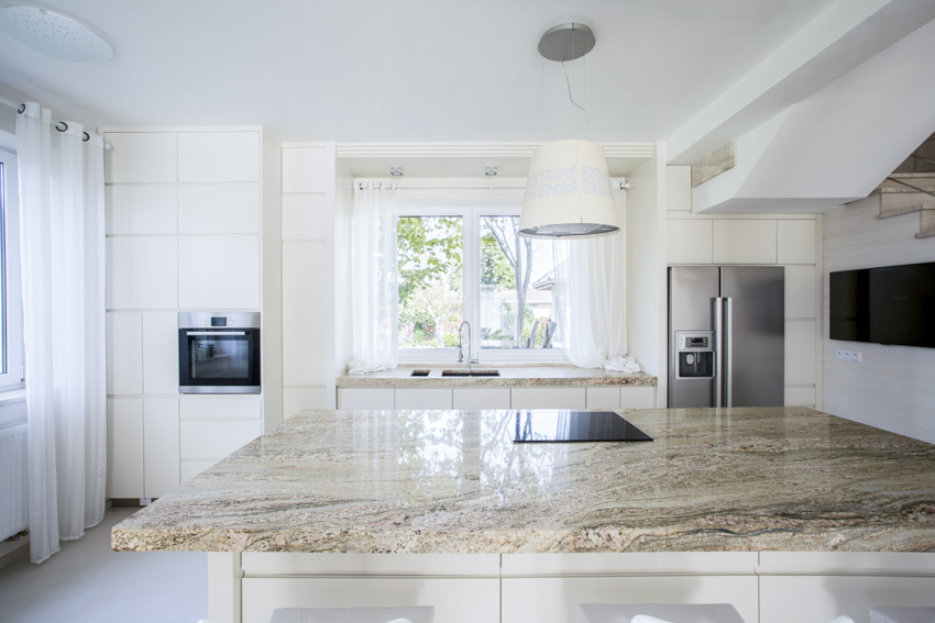 Kitchen with granite countertop, windows, refrigerator and cabinets