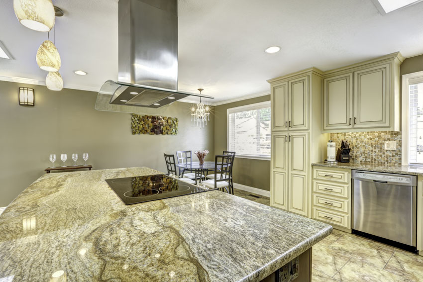 Kitchen with fantasy brown granite countertops, island, range hood, cabinets, and windows