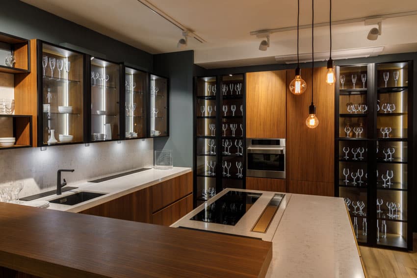 Kitchen with glass cabinets, countertops, sink, faucet, and pendant lights