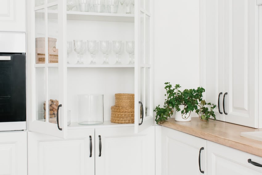 Cabinet with open doors, wine glasses and potted plant