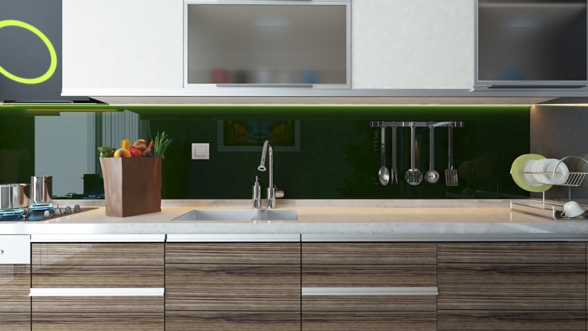 Kitchen with glass sheet backsplash, countertop, cabinets, and kitchenware