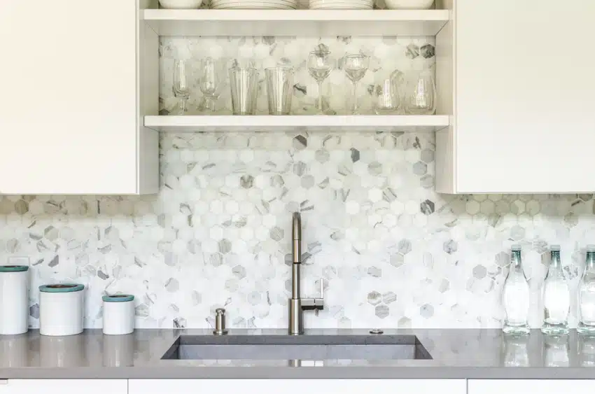 Kitchen with hexagon tile backsplash, sink, faucet, countertop, and cabinets
