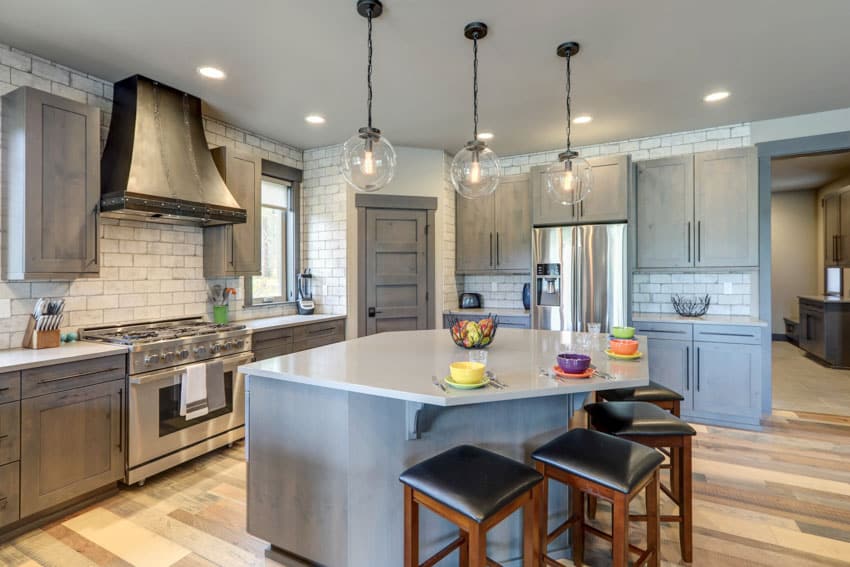 Kitchen with island, bar stools, pendant lights, tile backsplash, range hood, oven, and gray washed cabinets