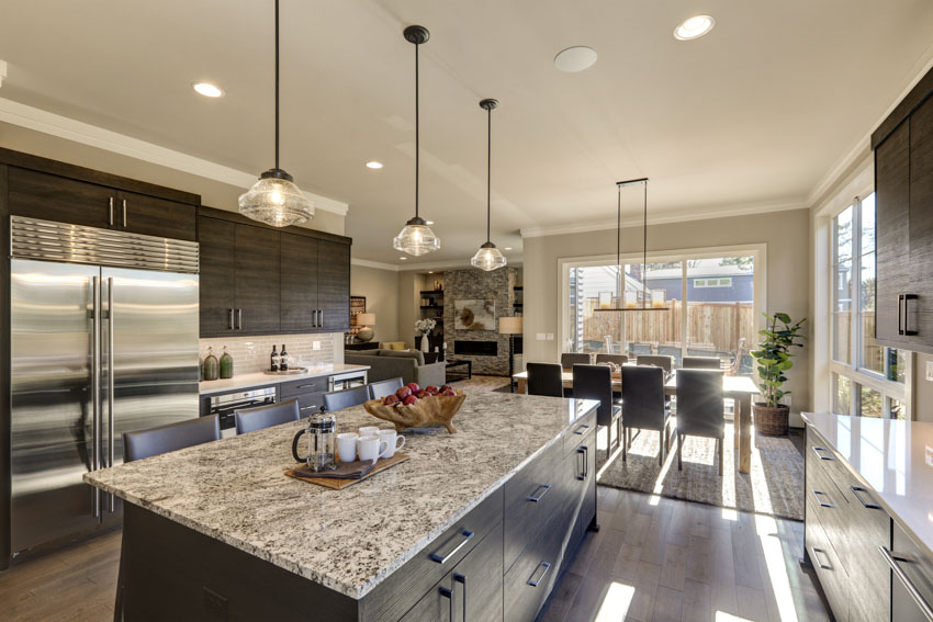 Kitchen with island, pendant lights, refrigerator, dining table, chairs, and granite countertop for families