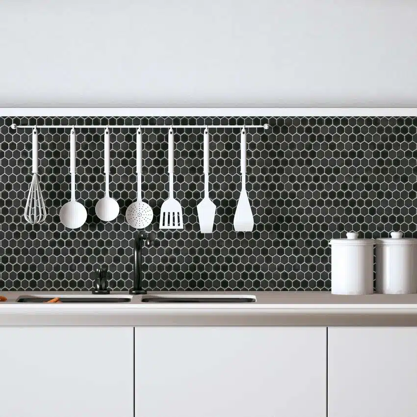 Kitchen with matte black hexagon tile backsplash, countertop, white cabinets, sink, faucet, and kitchenware
