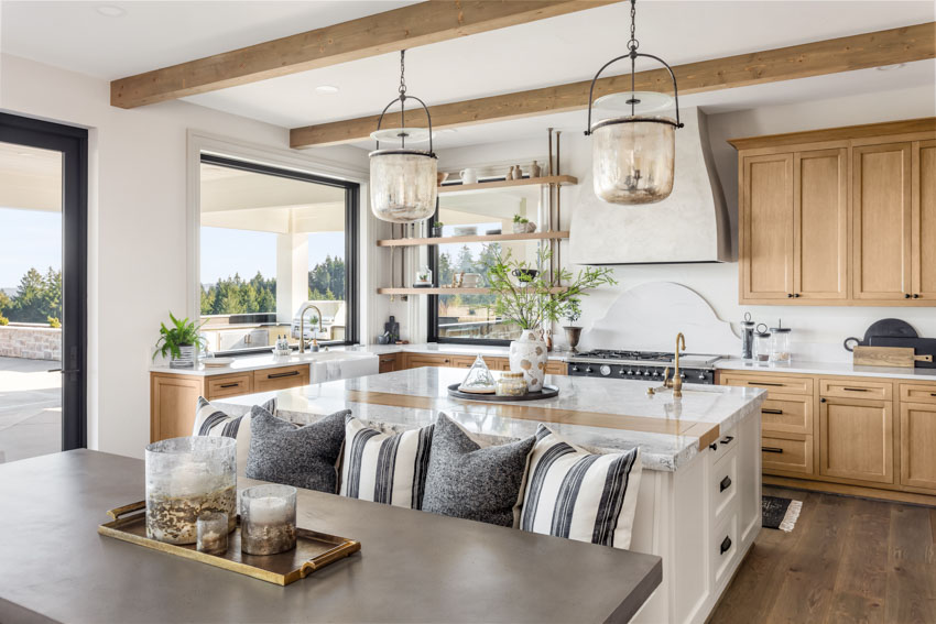 Kitchen with oak cabinets, marbled countertop, pendant lights, backsplash, exposed wood ceiling beams, nook seating, table, and windows