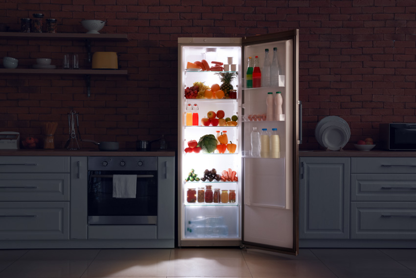 Kitchen with open refrigerator, cabinets, brick backsplash, and shelves