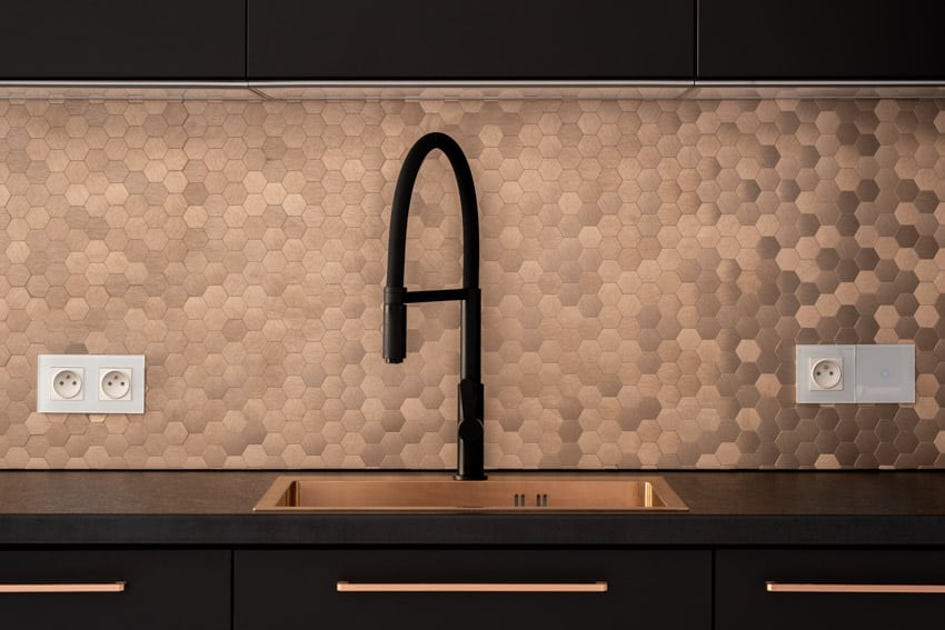 Modern kitchen with copper penny tile backsplash, countertop, sink, and black finished faucet