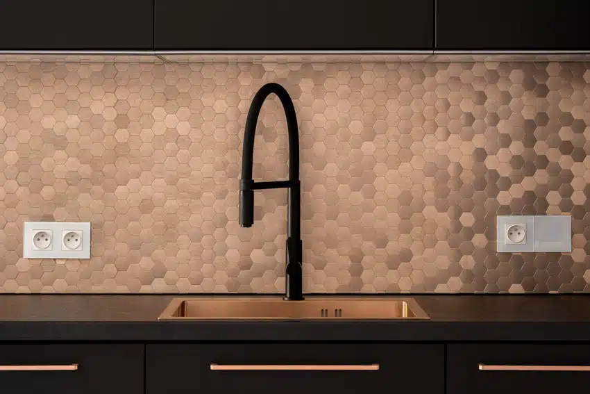 Kitchen with small hexagon tile backsplash, countertop, sink, and black finished faucet
