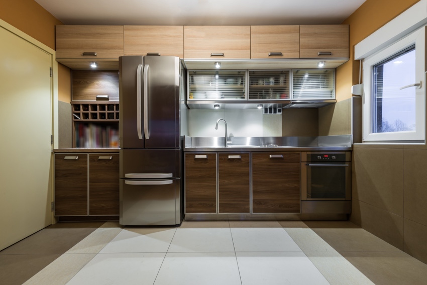 Kitchen with stainless steel refrigerator, cabinets, backsplash, tile flooring, and windows