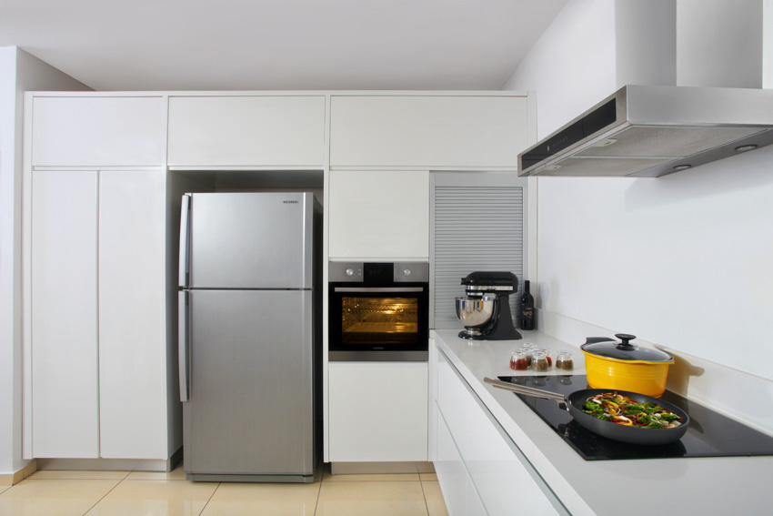 Kitchen with top freezer refrigerator, cabinets, oven, countertop, stove, and range hood
