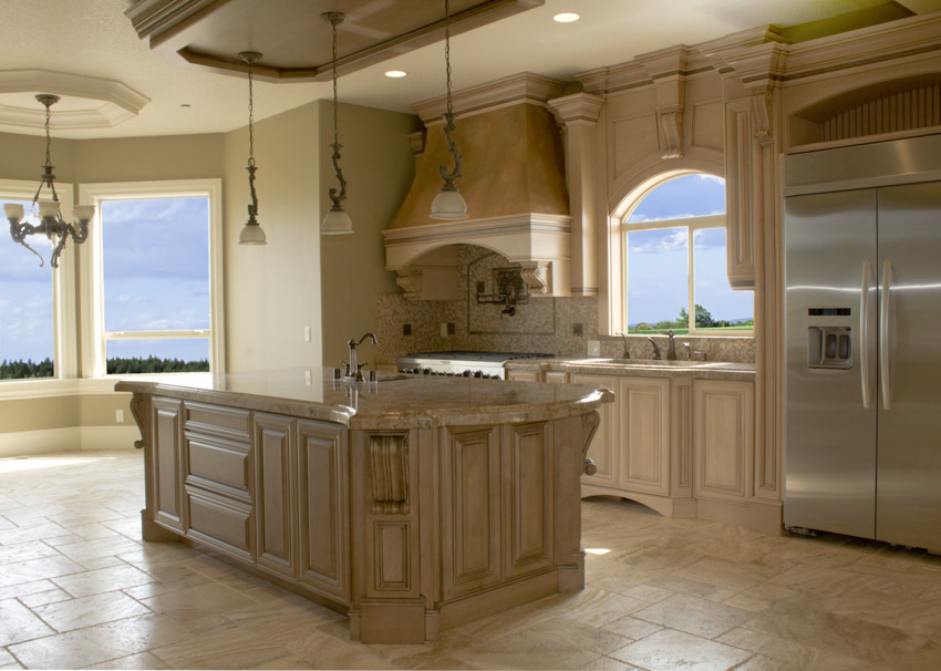 Kitchen with travertine countertops, backsplash, tile flooring, island, pendant lights, refrigerator, and windows