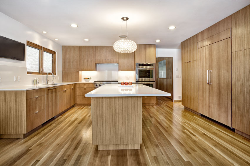 Kitchen with white countertops, oak cabinets, wood flooring, pendant lighting, backsplash, and windows