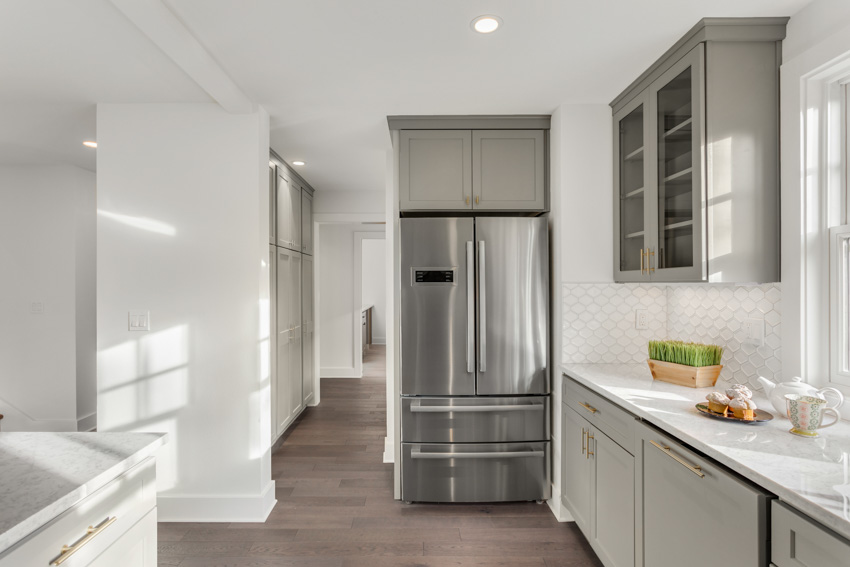 Kitchen with white-pained walls, cabinets, refrigerator, countertop, and ceiling light
