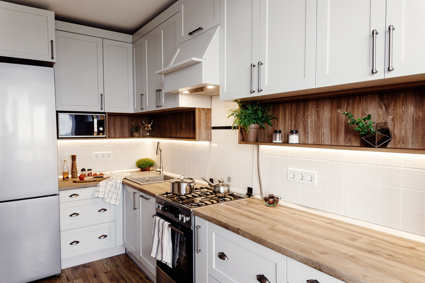 Kitchen with wood countertop, backsplash, cabinets, refrigerator, and wooden floors