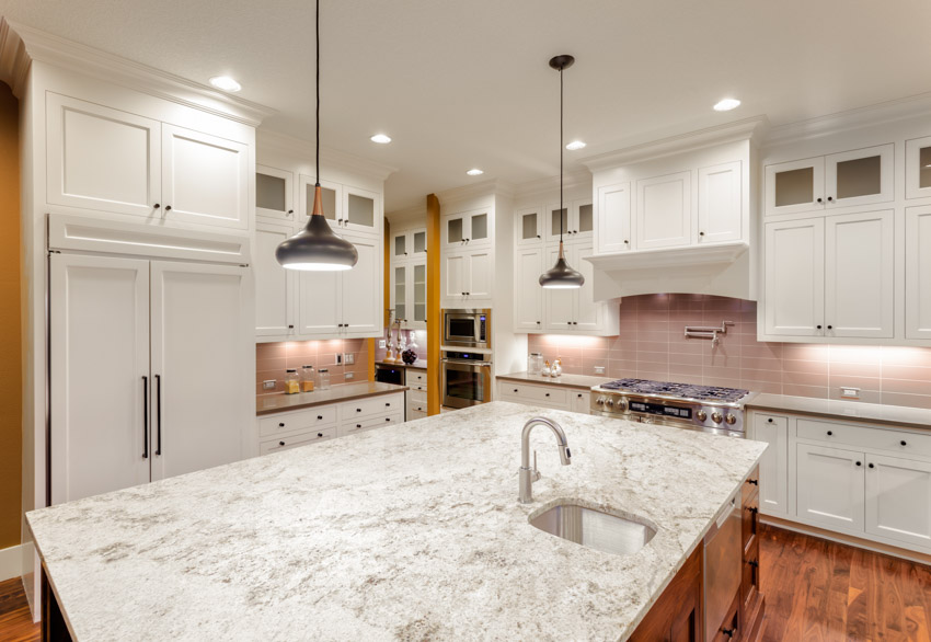 Kitchen with wood floors, granite top island and pink tile backsplash 