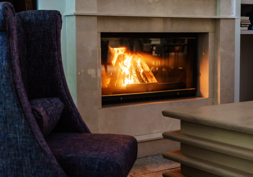 Room with dark purple chair and fireplace recessed into wall