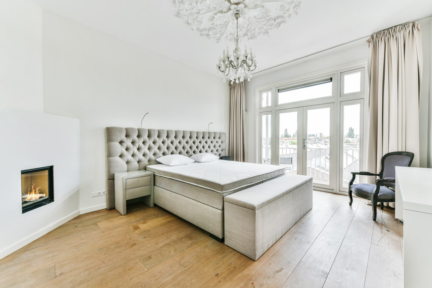 Bedroom with tufted headboard, bench at the foot of the bench, crystal chandelier