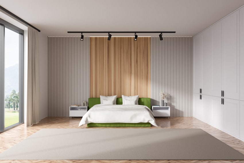 Minimalist bedroom with floor to ceiling beadboard wall, bed, track lighting, nightstands, and window