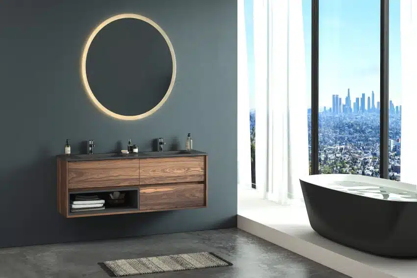 Modern bathroom with acacia cabinet, double sink, oval mirror, concrete flooring, and black bathtub